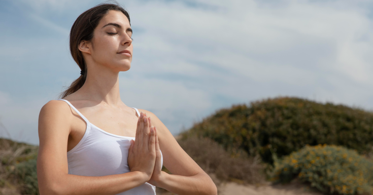 Mulher realizando exercício respiratório e de meditação ao ar livre